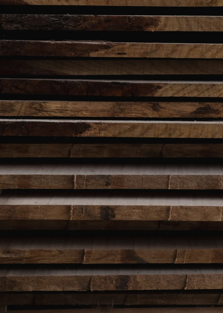 Planches de bois massif empilées à l'atelier MT Univers