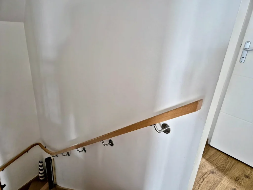 Main courante en bois fixée au mur de l’escalier